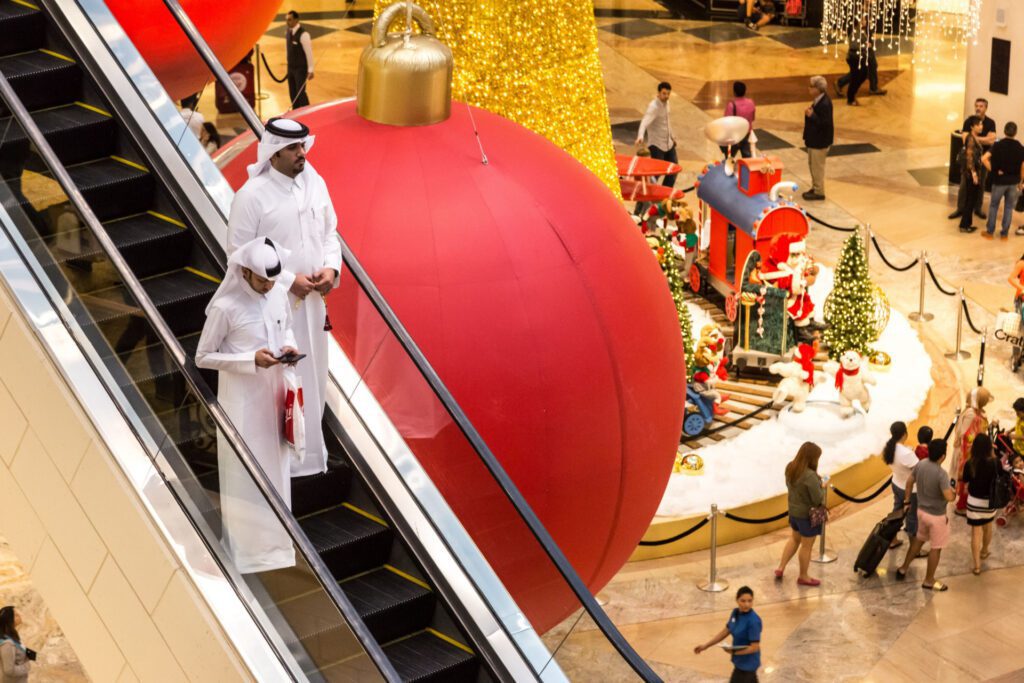 Emirati men walk past Christmas decorations in a mall in Dubai