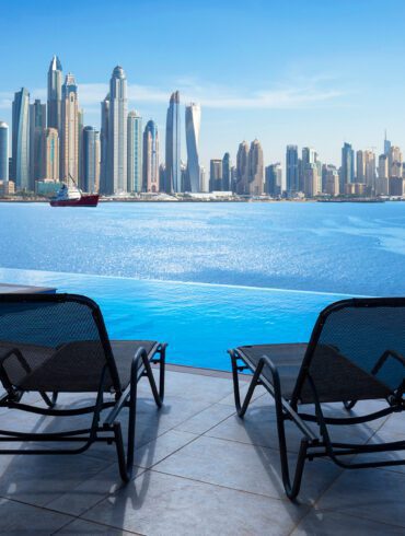 Infinity swimming pool in Dubai with city skyline view and blue sky