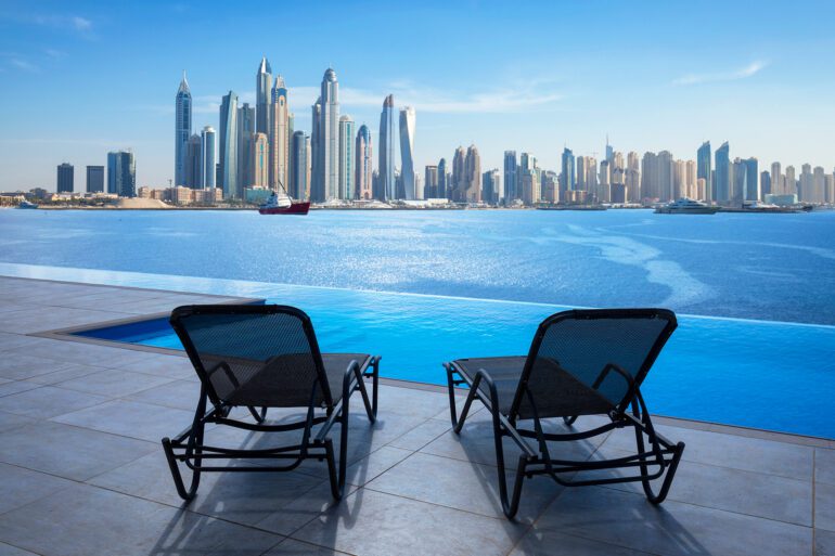 Infinity swimming pool in Dubai with city skyline view and blue sky