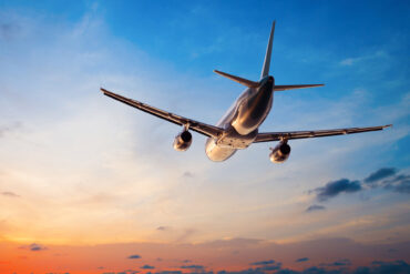 Plane flying through sunset sky