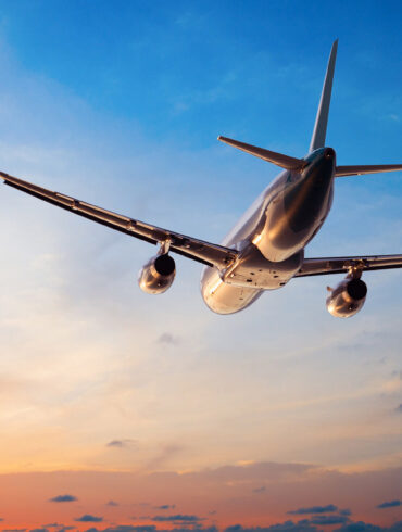 Plane flying through sunset sky